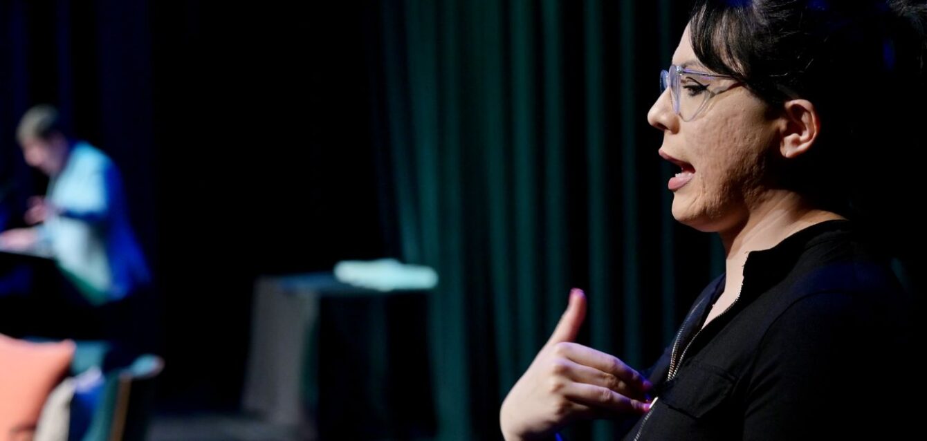 Dylan M. Rafaty speaking while interpreter signing American Sign Language
